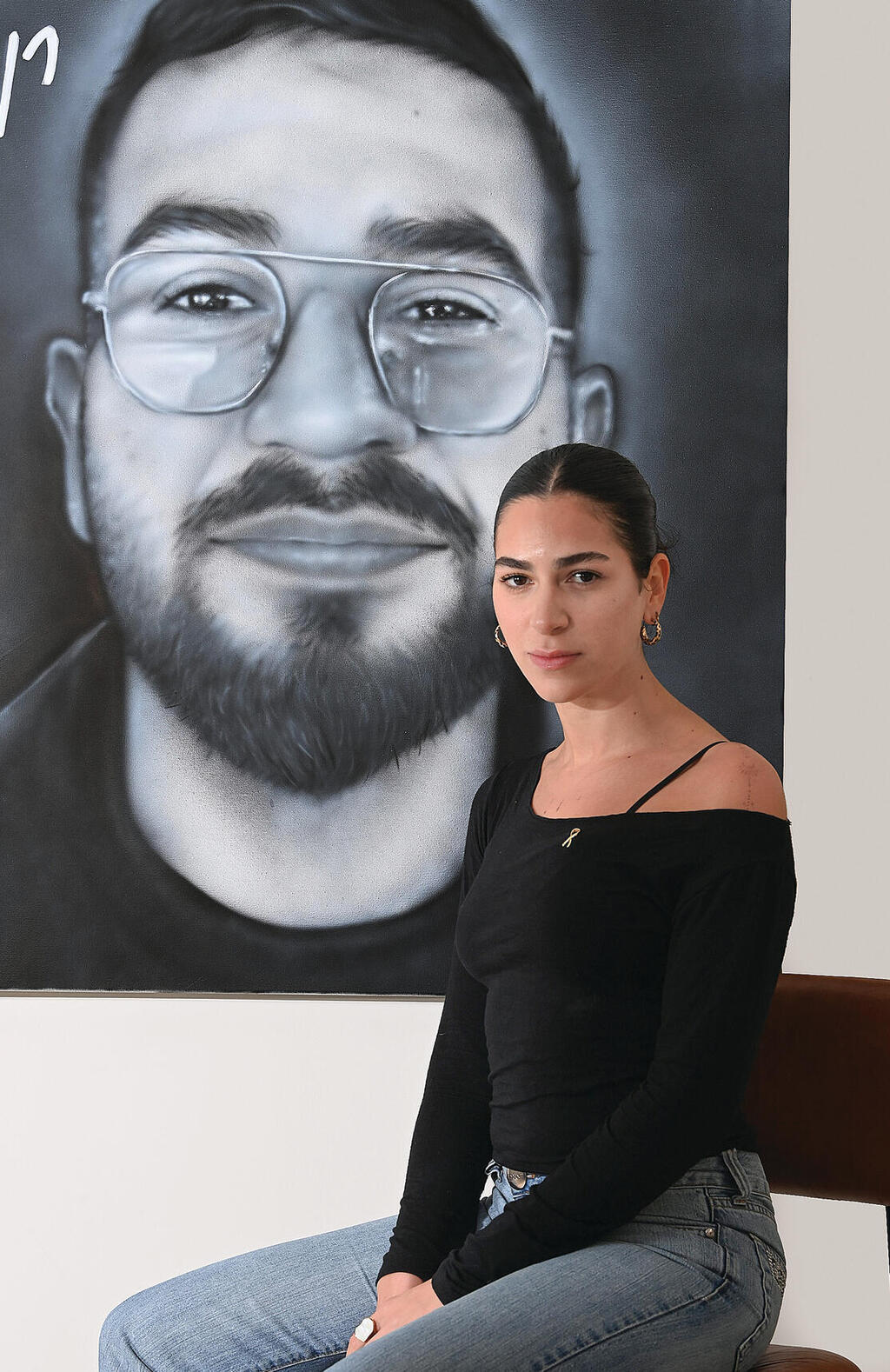 שירה גואילי על רקע דיוקנו של רן, השבוע. "המאבק זה הג'וב 'הנחשק' שלי והוא בחר אותי. אני מקווה שרני גאה בי" | צילום: הרצל יוסף