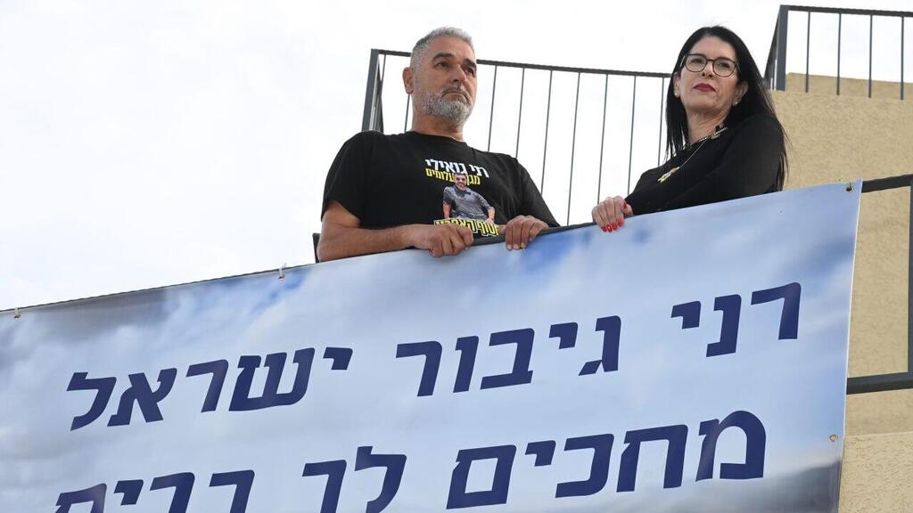 Ицик и Талик Гвили, родители Рана, с плакатом: "Рани, герой Израиля, ждем тебя дома" (Фото: Герцль Йосеф) טליק ואיציק גואילי