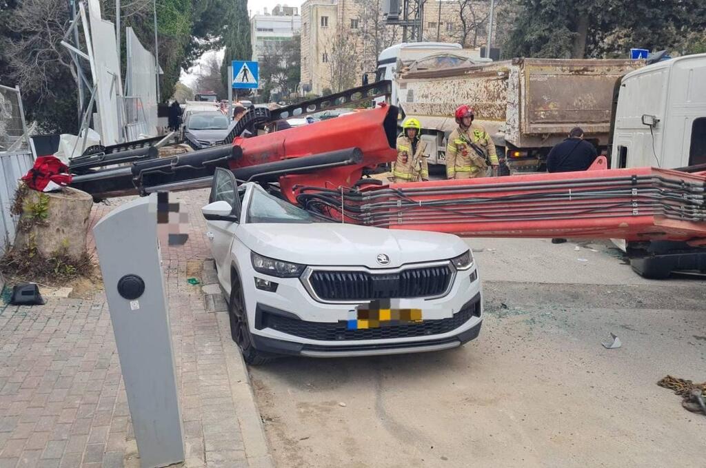 A crane truck lies overturned in Jerusalem on Jan. 28, 2026, after collapsing onto a vehicle during high winds. A woman in her 70s was killed in the incident. Police detained three people connected to the construction work nearby (Photo: Magen David Adom) משאית מנוף התהפכה