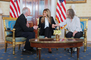 First lady Melania Trump, Keith Siegel (L) and Aviva Siegel (R) holds hands during a meeting in the Blue Room of the White House 
