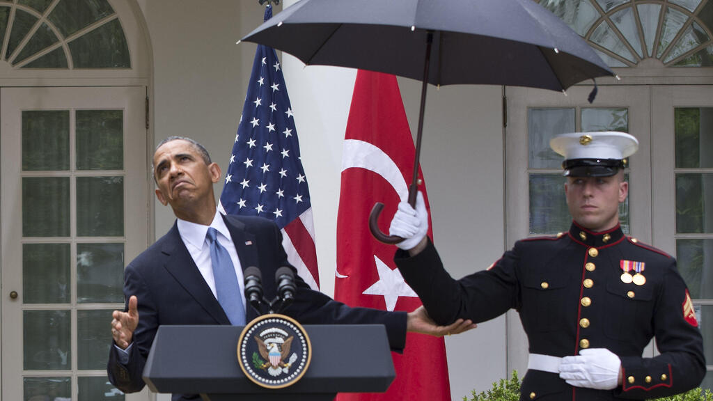 Obama and the umbrella incident (Photo: AP Photo/Jacquelyn Martin) חייל מחזיק מטרייה מעל ברק אובמה , 2013