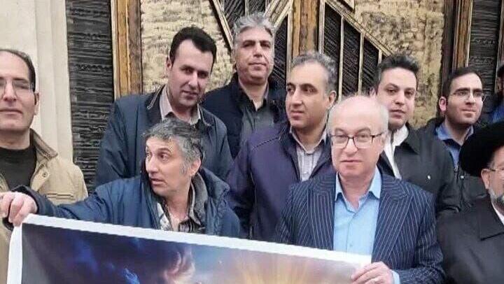 שמח עם שלט לצד חכם חמאמי ועליו הכיתוב "22 בבהמן, יום המהפכה האיסלאמית, הוא יום התגברות האור על החושך"