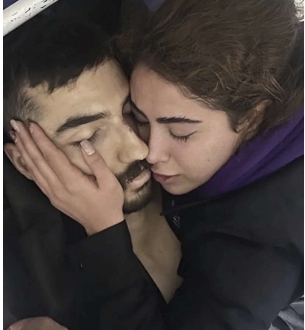The lifeless body of Matin Ghorbani, a protester killed by security forces, is embraced by his fiancée, Mahsa 