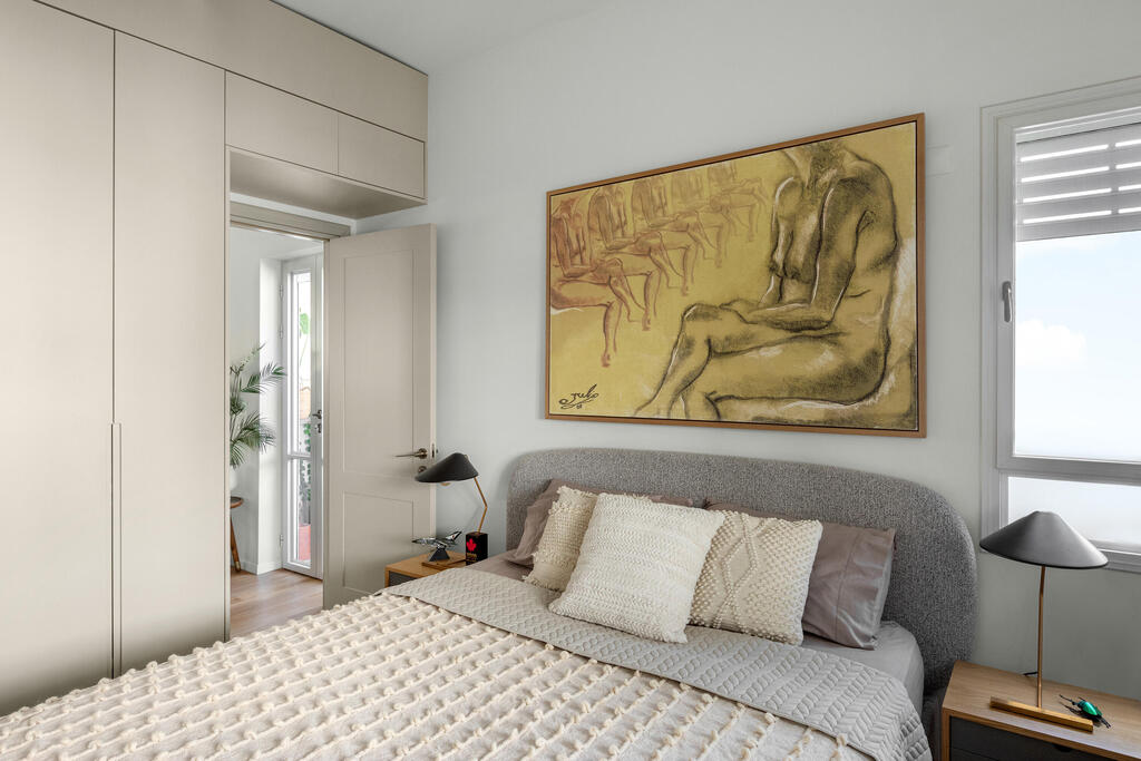 The couple’s bedroom. Above the bed is a painting by the designer (Photo: Shiran Carmel) שיפוץ דירה בתל אביב, עיצוב: יוליה חנדז'י
