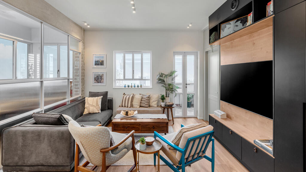 The living room surrounded by glass doors and leads to the balcony and the mother’s home office (Photo: Shiran Carmel) שיפוץ דירה בתל אביב, עיצוב: יוליה חנדז'י