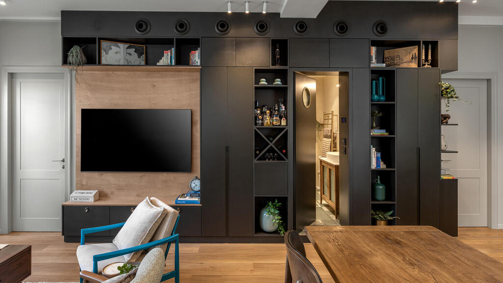 The library unit combines TV, storage and passage to a bathroom (Photo: Shiran Carmel) שיפוץ דירה בתל אביב, עיצוב: יוליה חנדז'י