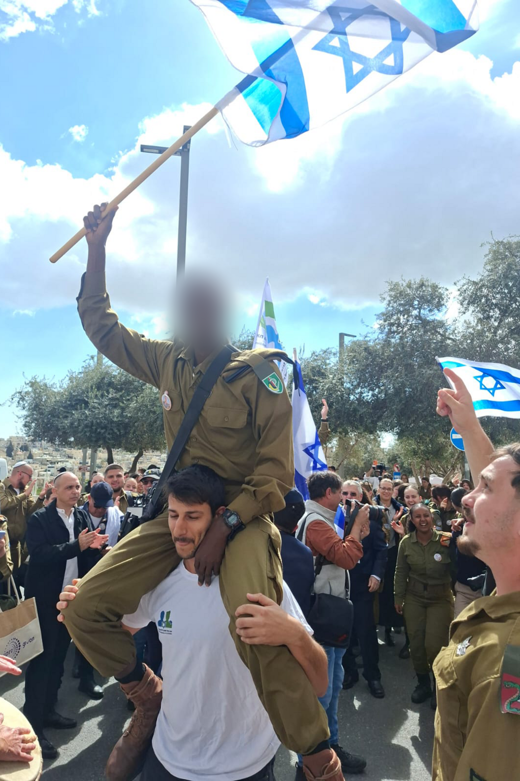 B. waves an Israeli flag during a ceremony held at the Western Wall plaza (Photo: Big Brother for Lone Soldiers) ב' מניף את דגל ישראל בטקס שנערך על רחבת הכותל המערבי