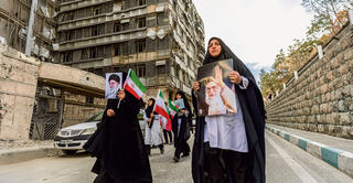 נשים איראניות עם תמונתו של חמינאי ליד בית חולים בטהרן שנהרס בהפצצות | צילום: Majid Saeedi , גטי אימג'ס