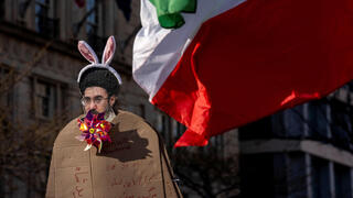 מתנגדי המשטר האיראני מניפים ב וושינגטון ארה"ב קרטון שלועג לדמותו של המנהיג העליון החדש ב איראן מוג'תבא חמינאי