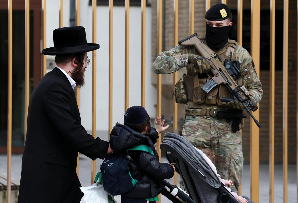 Security in an ultra-Orthodox neighborhood in Antwerp (Photo: Yves Herman/Reuters) ילד מנוף לשלום לאחד החיילים החמושים שמאבטחים את בתי הכנסת בבלגיה