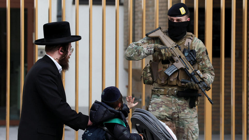 ילד מנוף לשלום לאחד החיילים החמושים שמאבטחים את בתי הכנסת בבלגיה
