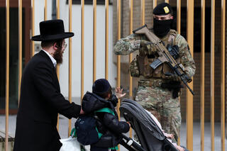 ילד מנוף לשלום לאחד החיילים החמושים שמאבטחים את בתי הכנסת בבלגיה