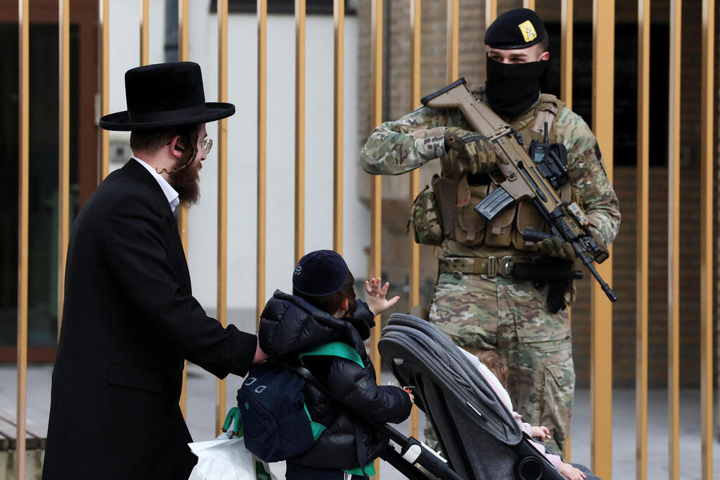 Военные охраняют синагоги в Бельгии (Фото: Yves Herman/Reuters) ילד מנוף לשלום לאחד החיילים החמושים שמאבטחים את בתי הכנסת בבלגיה