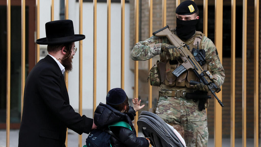 Бельгийский солда охраняет синагогу в Антверпене (Фото: Yves Herman/Reuters) ילד מנוף לשלום לאחד החיילים החמושים שמאבטחים את בתי הכנסת בבלגיה