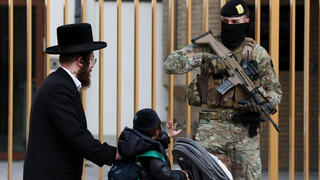 ילד מנוף לשלום לאחד החיילים החמושים שמאבטחים את בתי הכנסת בבלגיה