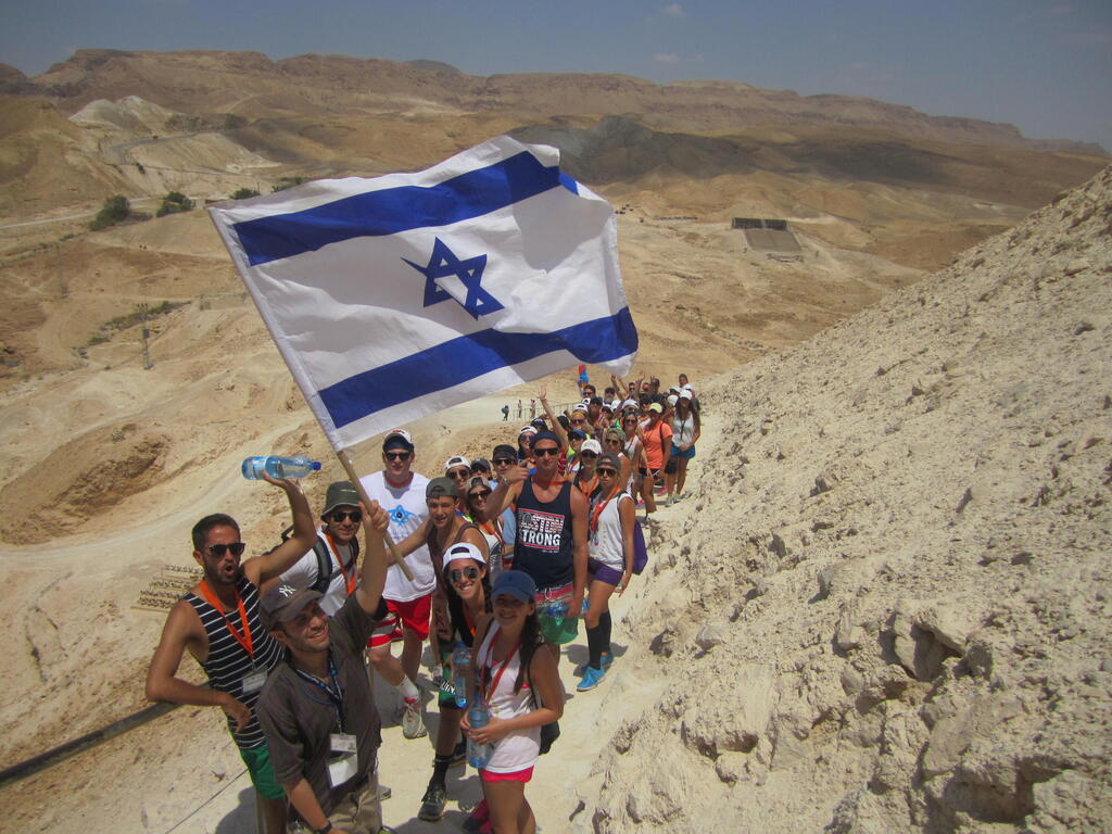 Participants on a Birthright Israel trip hike in the Judean Desert while carrying an Israeli flag (Photo: Birthright Israel) Participants on a Birthright Israel trip hike in the Judean Desert while carrying an Israeli flag