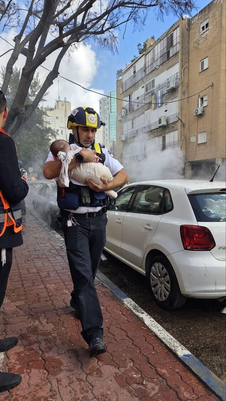 Magen David Adom medic carries an infant rescued from an impact site in Petah Tikva תינוק בזירה
