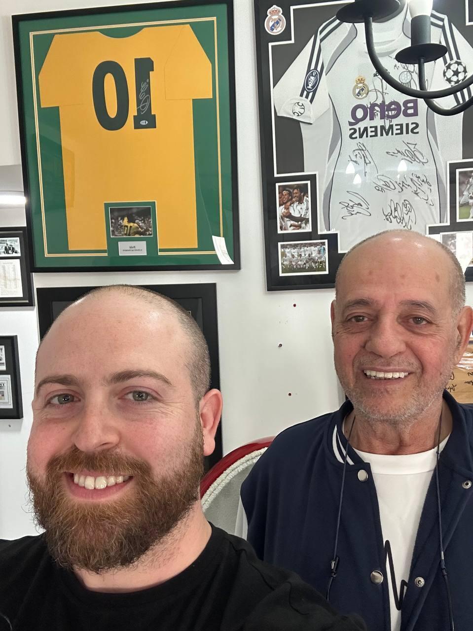 Bar Gindy, left, host of the People and Collectors podcast, poses with collector Erez Kaminski in front of framed sports memorabilia 
