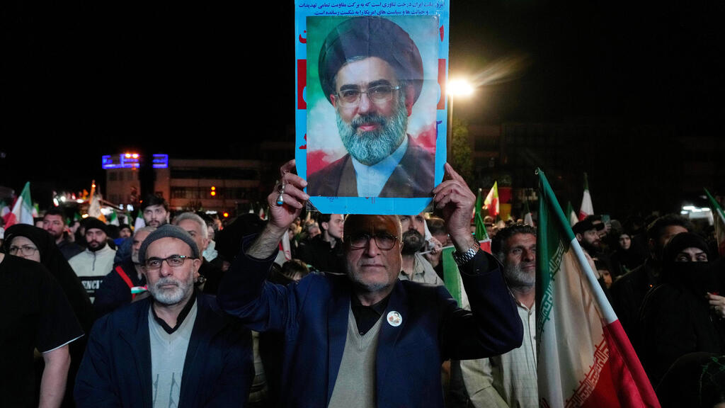 תומכי המשטר האיראני מניפים את תמונתו של מוג'תבא חמינאי לאחר ההודעה על הפסקת האש
