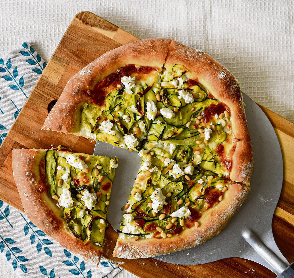 White pizza with zucchini ribbons, cheese and pine nuts