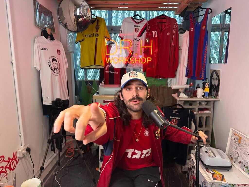 Sahar Haba sits in his studio in Tel Aviv’s Florentin neighborhood, surrounded by jerseys and memorabilia tied to his life as a Hapoel Jerusalem supporter and sneaker artist 