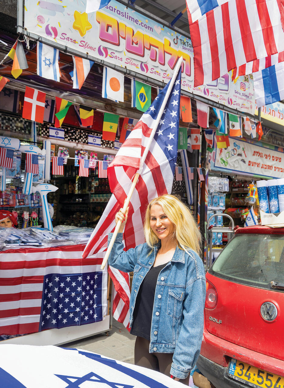 רוית, בתו של חיים בוהדנא, בכניסה לחנות המשפחתית בדרום תל־אביב. מכרו כבר  10,000 דגלי ארה"ב | צילום: אביגיל עוזי