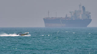 סירה קטנה שטה ליד מכלית ספינה סמוך לאי האיראני קשם  מצר הורמוז שנחסם על ידי איראן