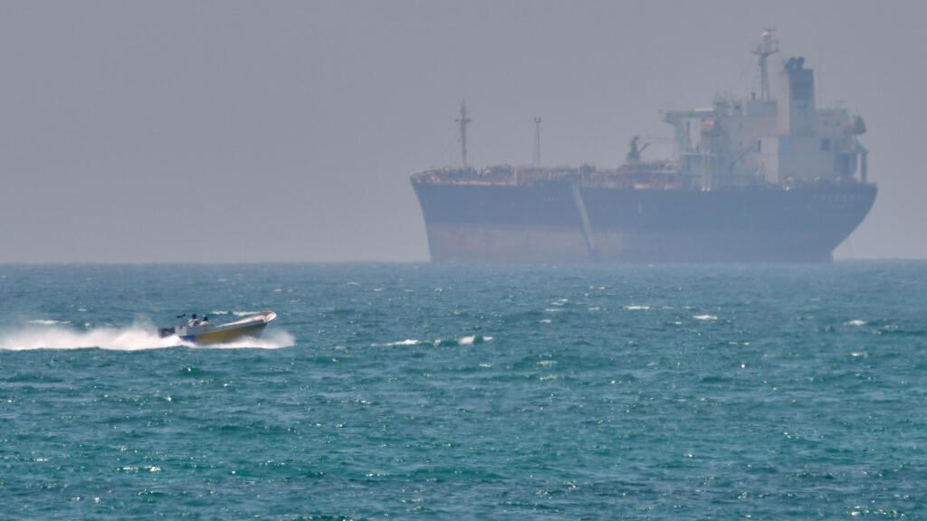 סירה קטנה שטה ליד מכלית ספינה סמוך לאי האיראני קשם  מצר הורמוז שנחסם על ידי איראן