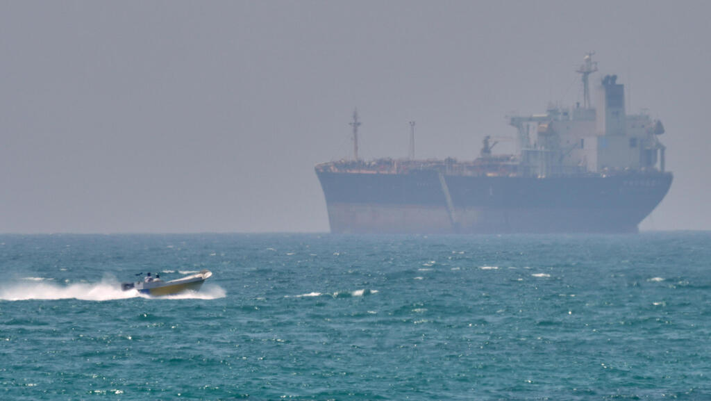 סירה קטנה שטה ליד מכלית ספינה סמוך לאי האיראני קשם  מצר הורמוז שנחסם על ידי איראן