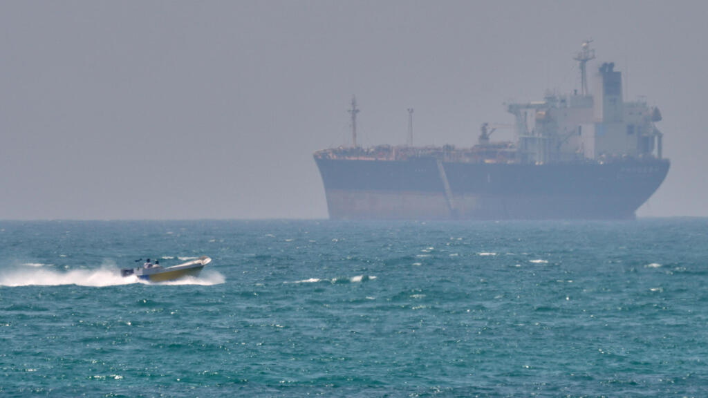 סירה קטנה שטה ליד מכלית ספינה סמוך לאי האיראני קשם  מצר הורמוז שנחסם על ידי איראן