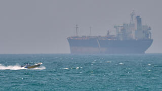 סירה קטנה שטה ליד מכלית ספינה סמוך לאי האיראני קשם  מצר הורמוז שנחסם על ידי איראן