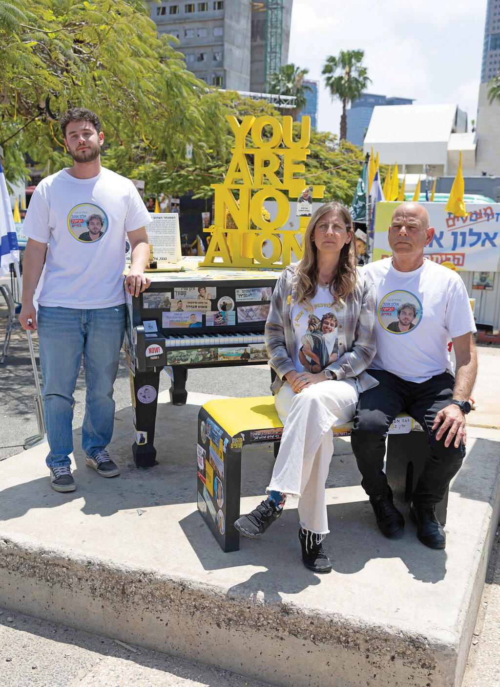 עידית, קובי ורונן אהל לצד הפסנתר שהוצב  לכבוד אלון בכיכר החטופים, אפריל 2
