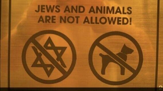שלט פוגעני שהוצב במלון בעיר אוש, בו נכתב שהכניסה לכלבים ויהודים אסורה