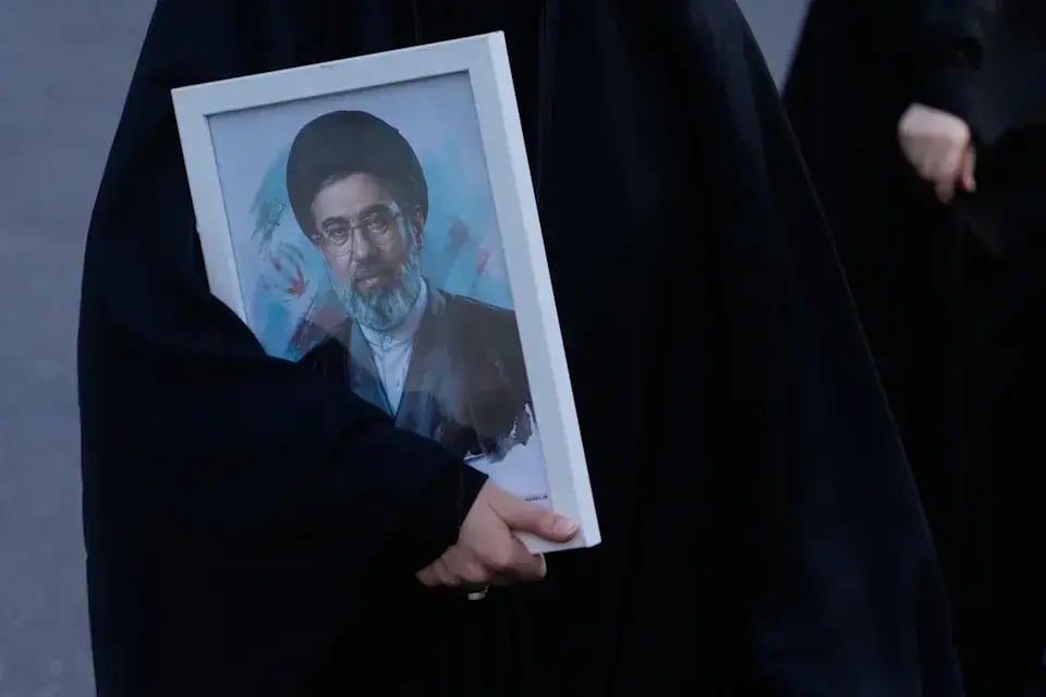 A woman holds a picture of the Iranian Supreme Leader Ayatollah Mojtaba Khamenei 