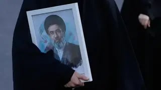 A woman holds a picture of the Iranian Supreme Leader Ayatollah Mojtaba Khamenei 
