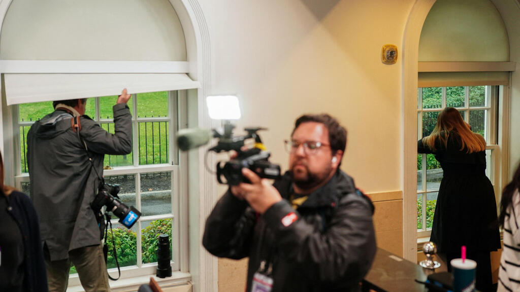 Journalists peek out of windows after the shooting near the White House (Photo: Nathan Howard/ Reuters) עיתונאים מציצים מהחלונות לאחר הירי בבית הלבן