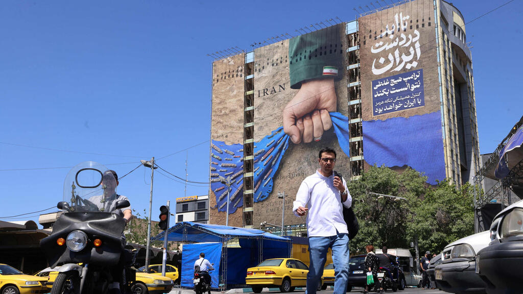 A giant billboard on a street in Tehran depicts the 'hand of Iran' gripping the Strait of Hormuz (Photo: ATTA KENARE / AFP) טהרן