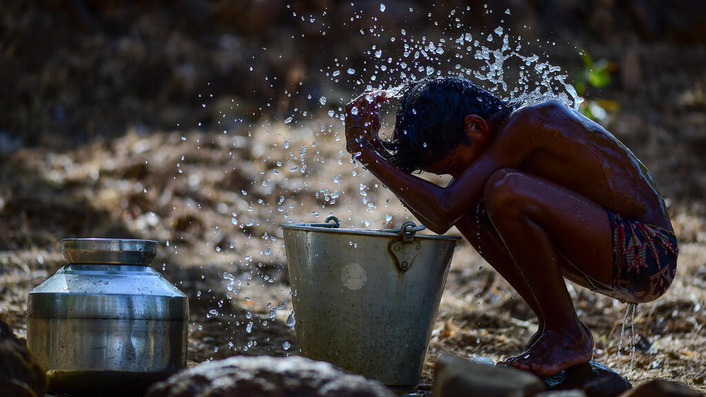 A child wets himself to cope with the heavy heat in India (Photo: Ritesh Shukla/Getty Images) ילד מרטיב את גופו כדי להתמודד עם החום הכבד בהודו