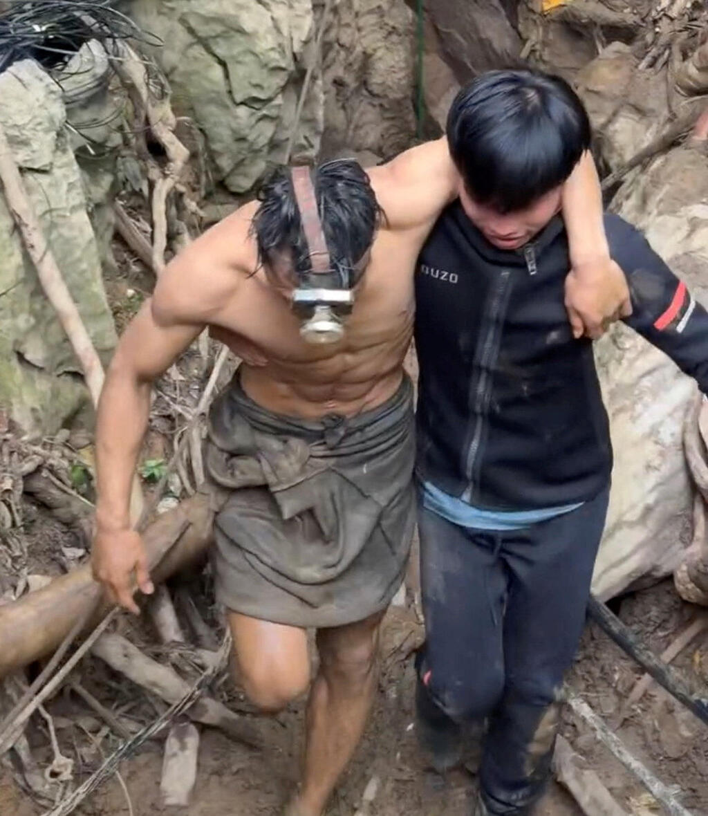 Mee Singfamalai is helped away from the cave by a rescuer (Photo: Chakkrit Taengtang/via Reuters) לכודים שזחלו בכוחות עצמם מ מערה ב לאוס 30 במאי