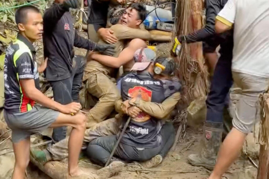 Trapped villager emerges from flooded cave and embraces rescuer (Photo: Handout / Adisak Wongsoraya/AFP) לכודים שזחלו בכוחות עצמם מ מערה ב לאוס 30 במאי