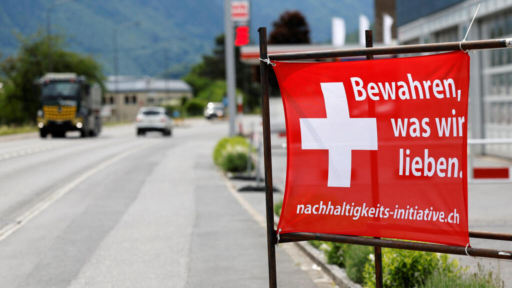 Poster by supporters of Swiss initiative, reading: 'Keep what we have'; Among the warnings: The housing shortage will increase (Photo: Stefan Wermuth/Reuters) שווייץ משאל עם על הגבלת האוכלוסייה כרזה לשמור על מה שיש לנו