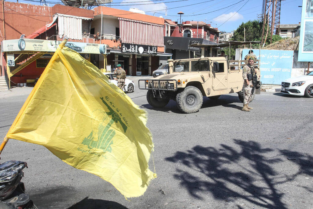 Hezbollah flag at the entrance to Nabatieh next to a Lebanese Army jeep (Photo: Mahmoud ZAYYAT / AFP) הכניסה ל נבטיה תושבים חוזרים הביתה