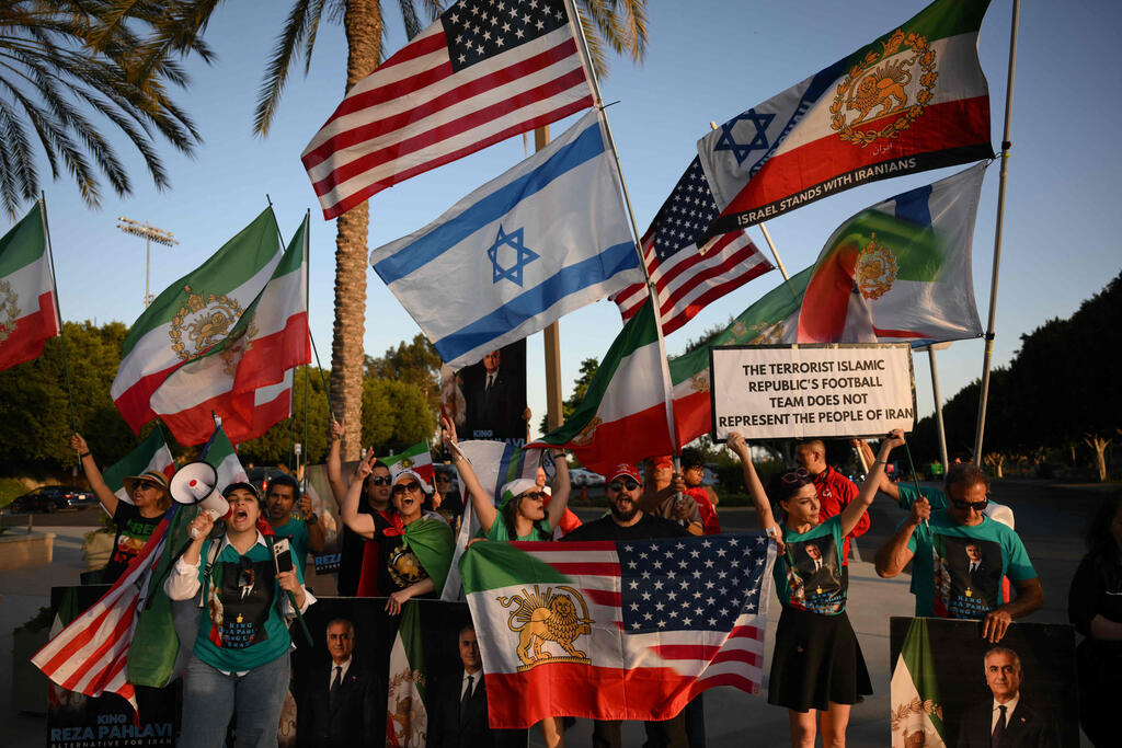 Iran fans beside an Israeli flag (Photo: Patrick T. Fallon / AFP) אוהדי איראן