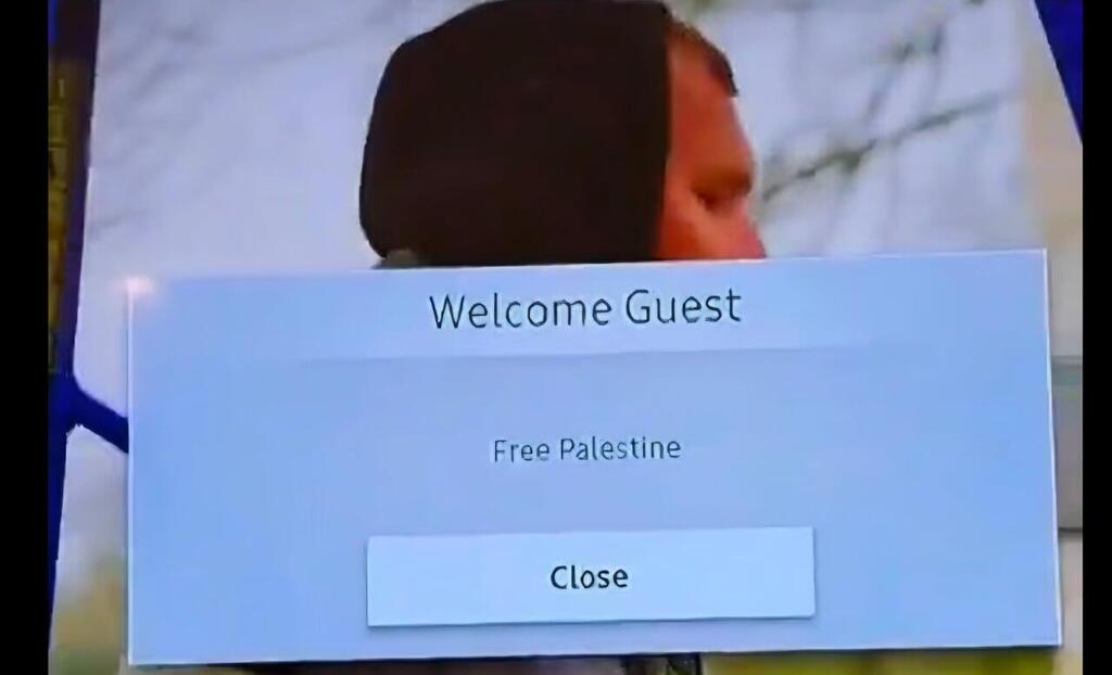 A television screen in a London Travelodge hotel room displays the message 'Welcome Guest – Free Palestine' הודעת "Free Palestine"