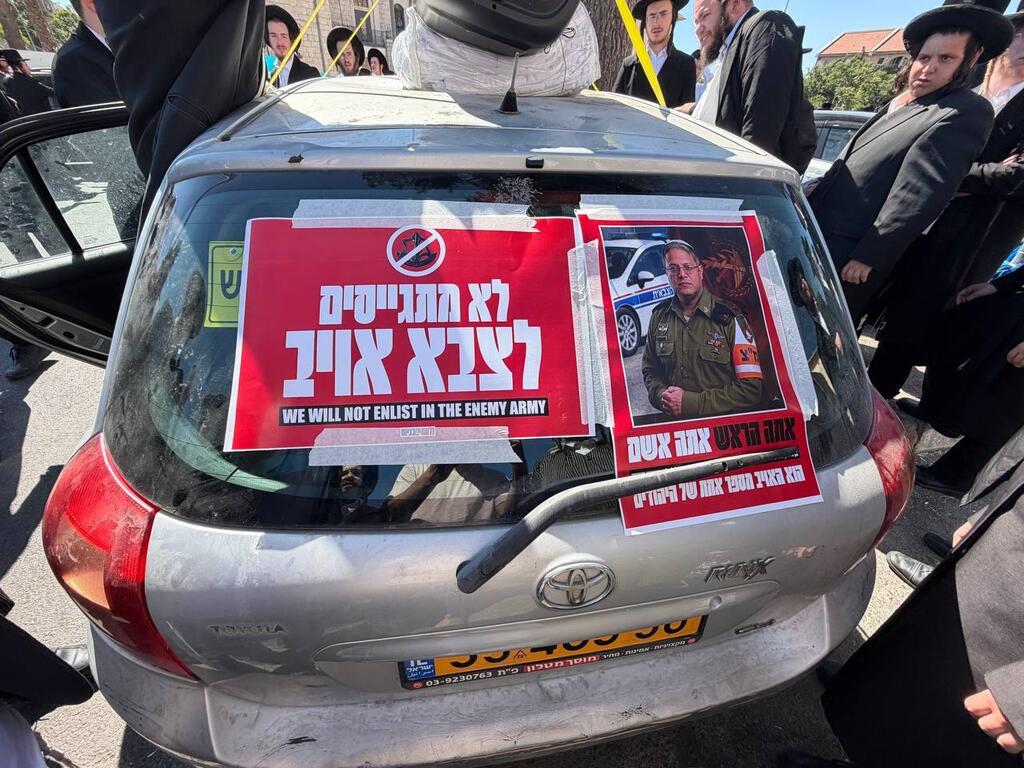 Ultra-Orthodox protesters place signs on a car during a convoy protest against military draft efforts. One poster depicts National Security Minister Itamar Ben-Gvir in military police uniform with the slogan, 'The Jews’ No. 1 enemy' (Photo: Idan Bloemhof) בן גביר במדים "אתה הראש אתה אשם"