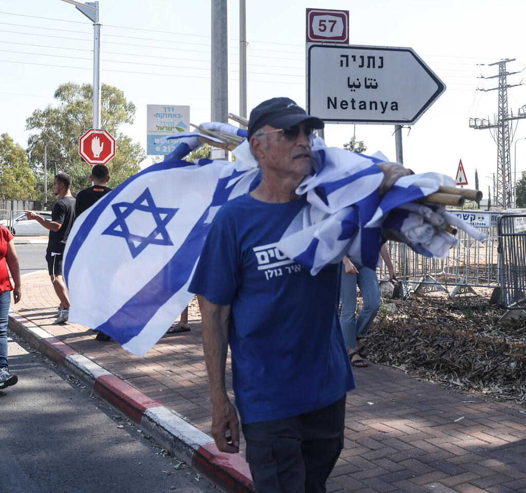 A Kfar Yona resident carries an Israeli flags during a counterprotest against ultra-Orthodox demonstrators seeking to reach nearby Military Prison 10 (Photo: Gil Nechushtan) מפגינים נגד החרדים בכפר יונה