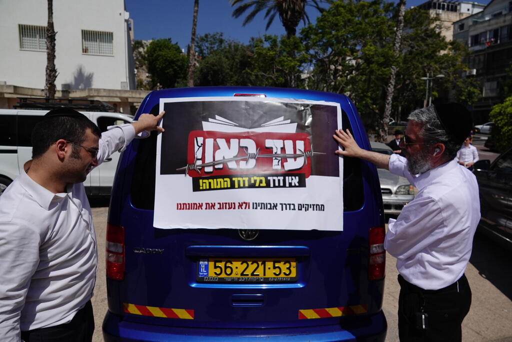 Ultra-Orthodox men attach a protest sign to a vehicle before joining a convoy against plans to draft yeshiva students (Photo: Shaul Golan) בני ברק