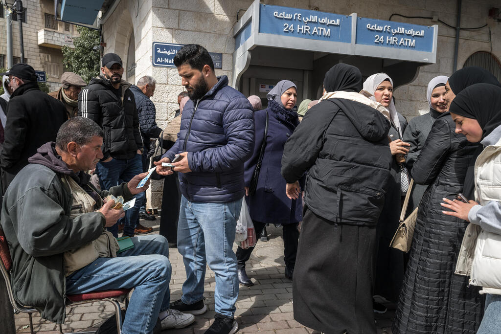 Palestinians exchange money at a bank terminal in Ramallah (Photo: Sergey Ponomarev/Getty Images) פלסטינים מחליפים כספים במסוף בנק ברמאללה