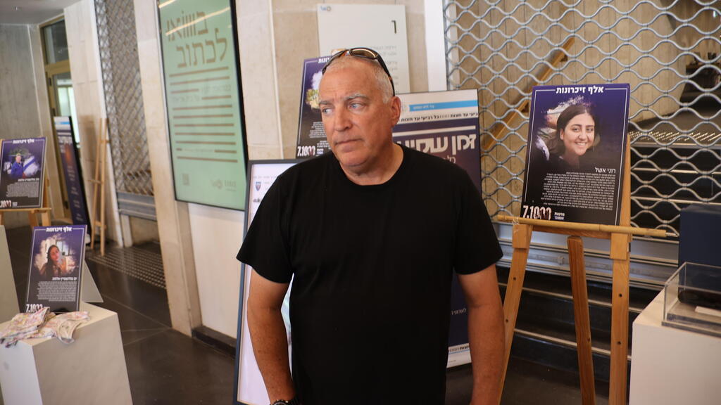 Eyal Eshel with a photo of his daughter, Roni, an IDF lookout who was killed on October 7 (Photo: Motti Kimchi) יו"ר האופוזיציה יאיר לפיד ועינב צנגואקר בתערוכת "1,000 זכרונות"