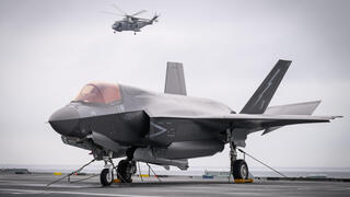 25 ביוני צבא בריטניה מסוק Merlin HM2 טס מעל מטוס קרב F-35B (דגם נחיתה והמראה אנכית של F-35 ) על גבי נושאת המטוסים הבריטית HMS Prince of Wales  במהלך תרגיל נאט"ו בים ליד נורבגיה 